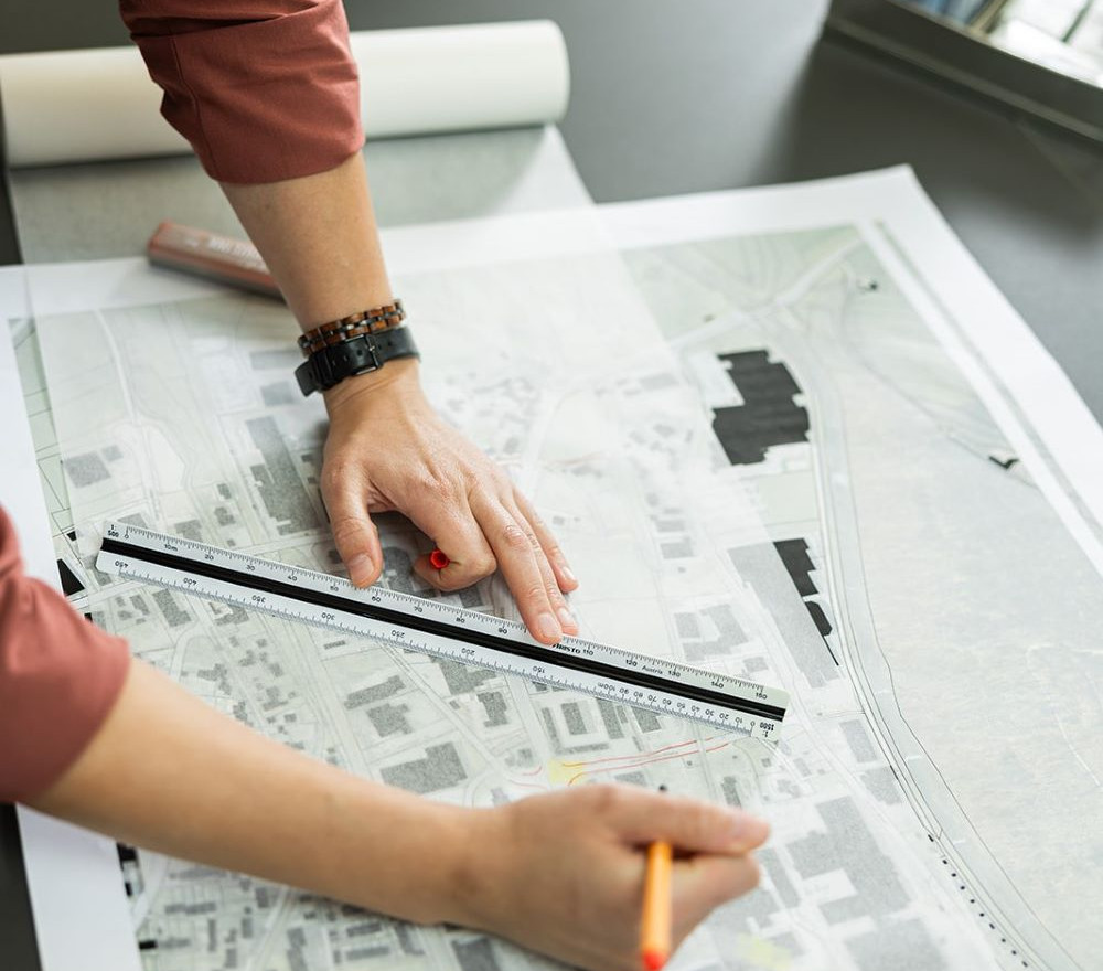 Person markiert mit Stift und Lineal Details auf einem Bauplan
