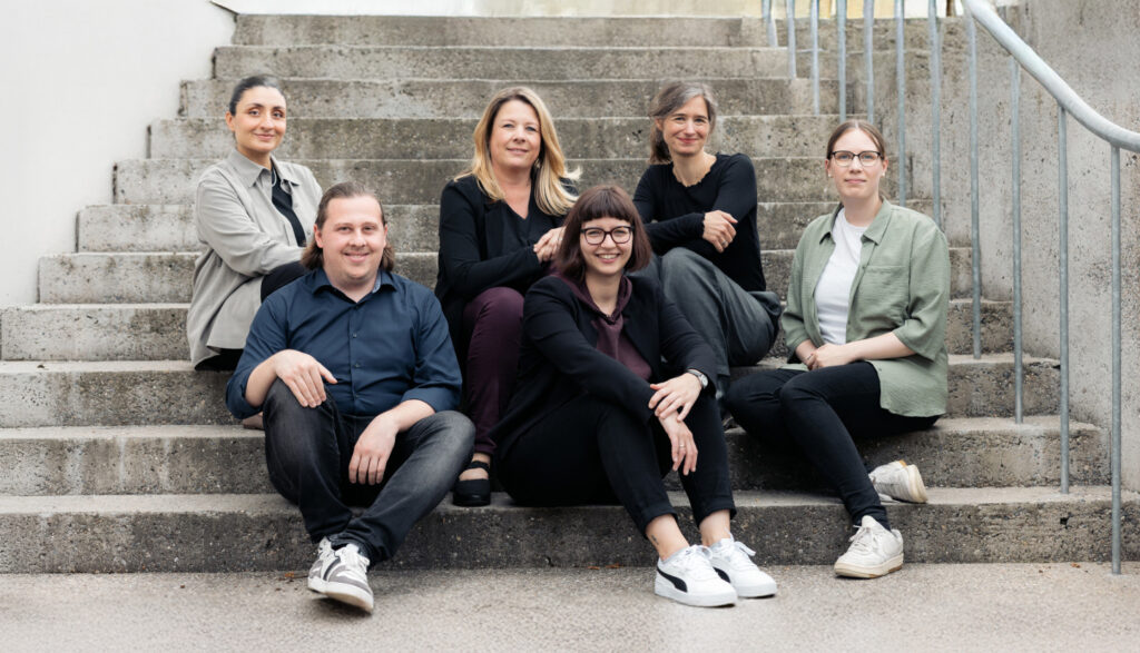 Team der Stadtbau Lörrach sitzt gemeinsam auf einer Treppe